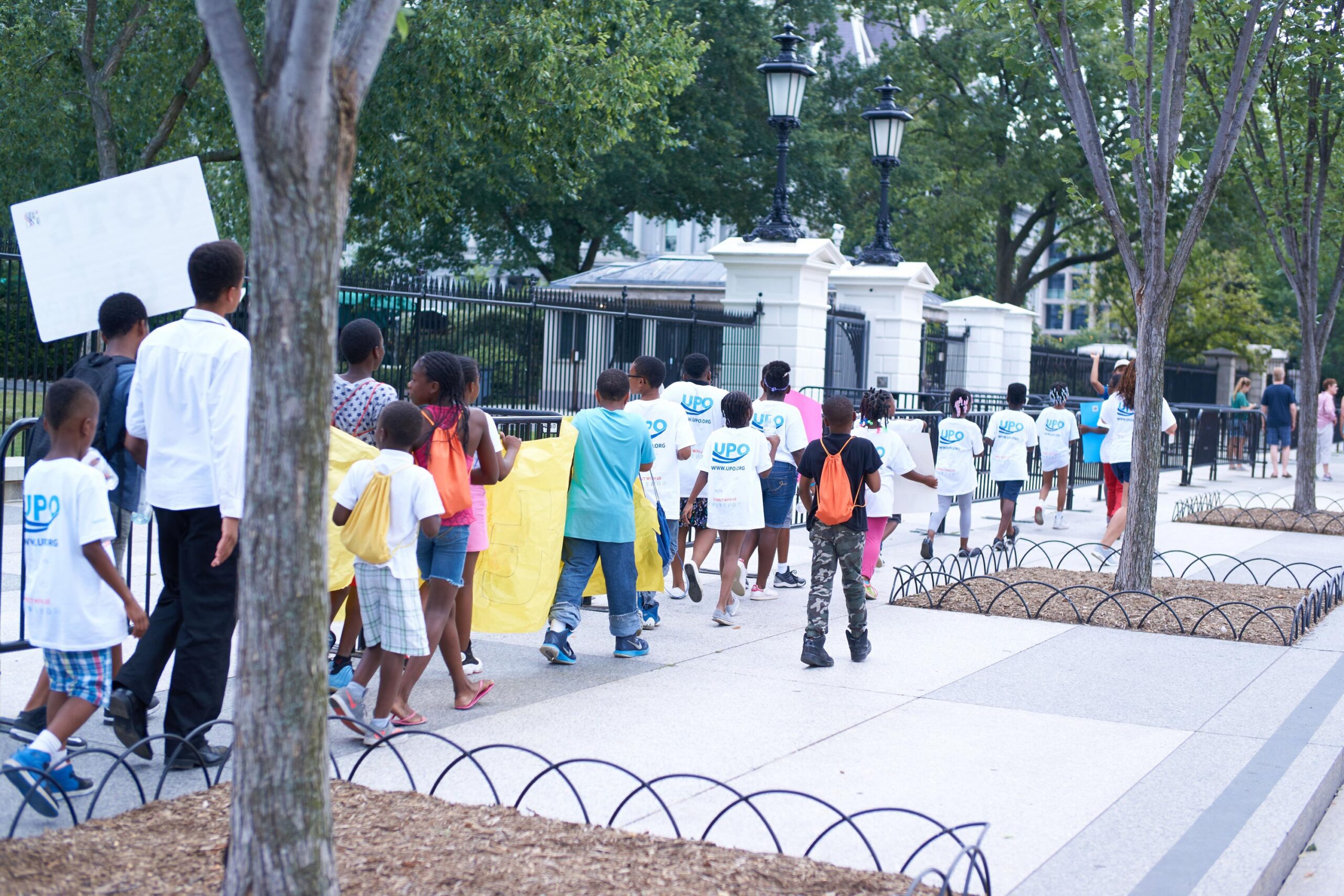 schoolchildren walk past the white house wearing UPO t-shirts and holding signs