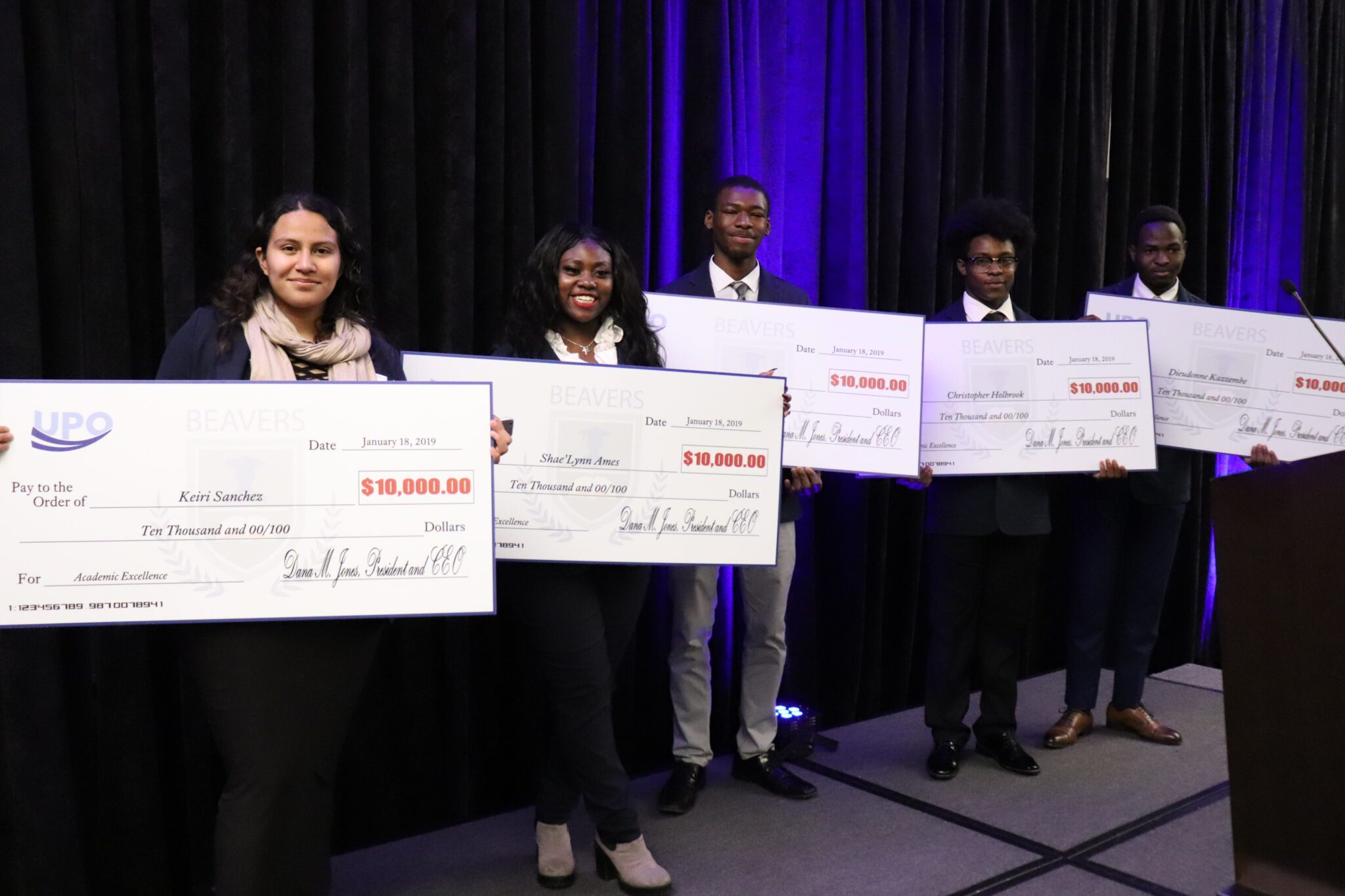 hispanic and black students holding giant scholarship checks