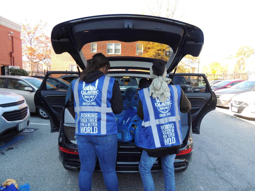 volunteers loading bags into the back of a car