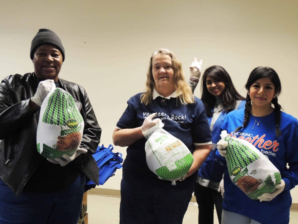 black man and women of multiple ethnicities posing holding frozen turkeys