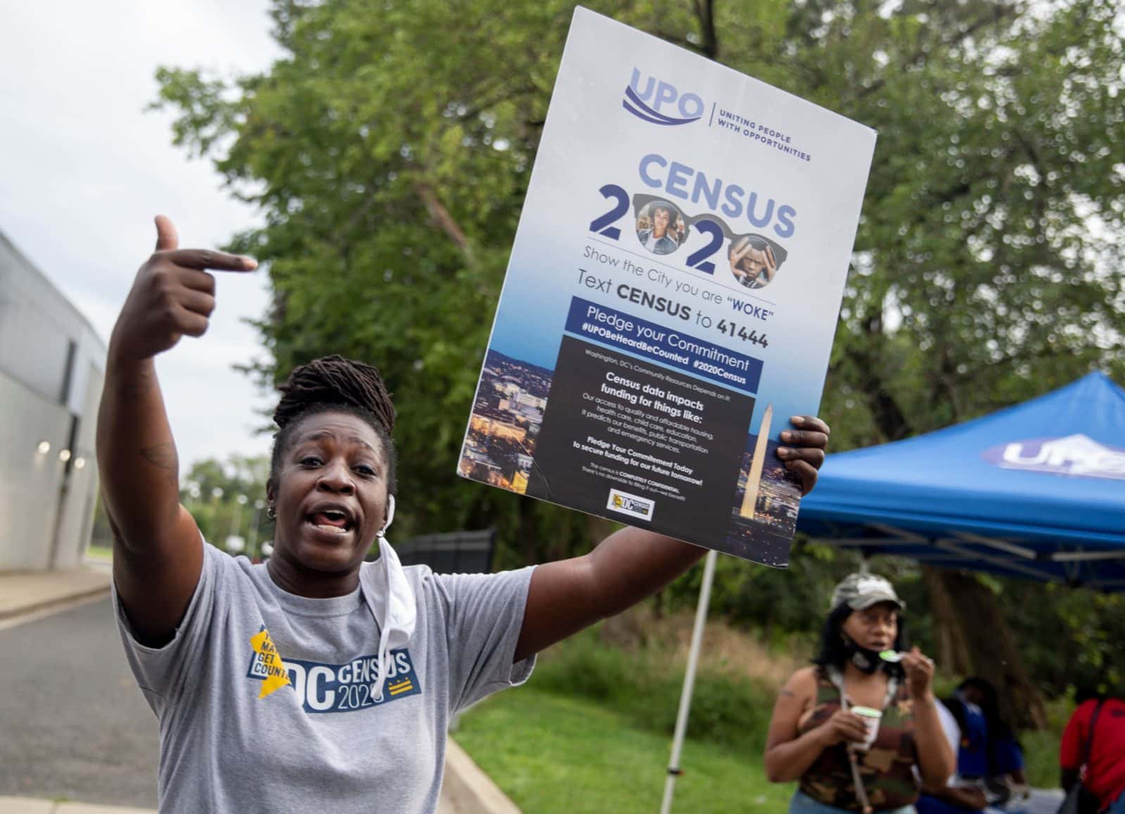 black woman hosting a census sign and calling out to passerby