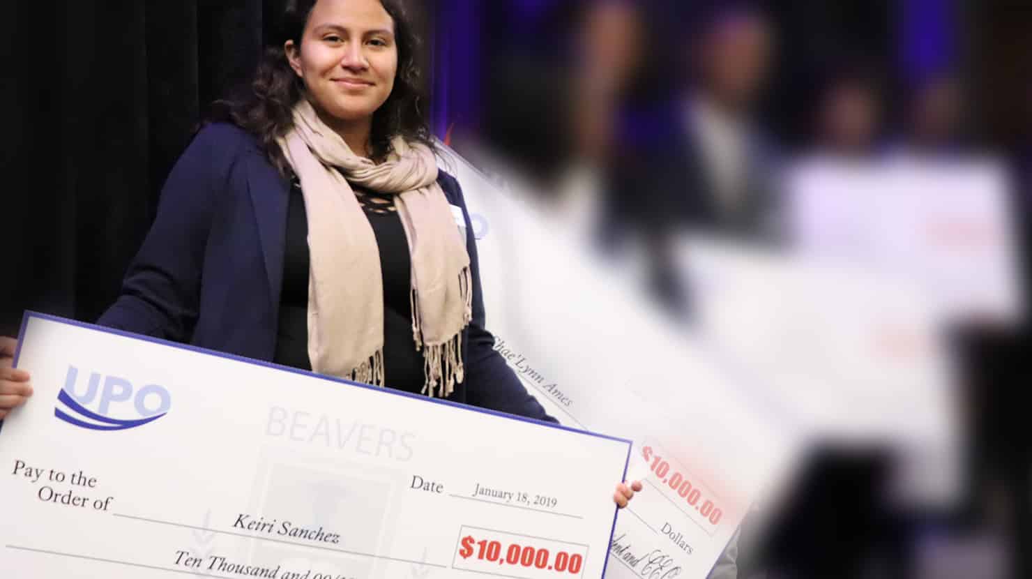 hispanic student holding giant scholarship check