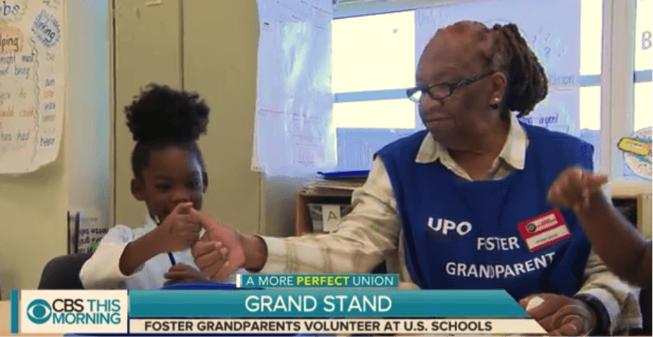 older black woman plays with a young black girl in a classroom