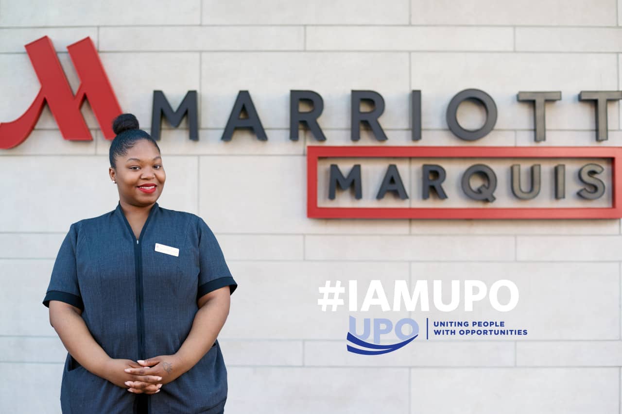 LaQuita next to Marriott Marquis sign and text "hashtag I am u p o"