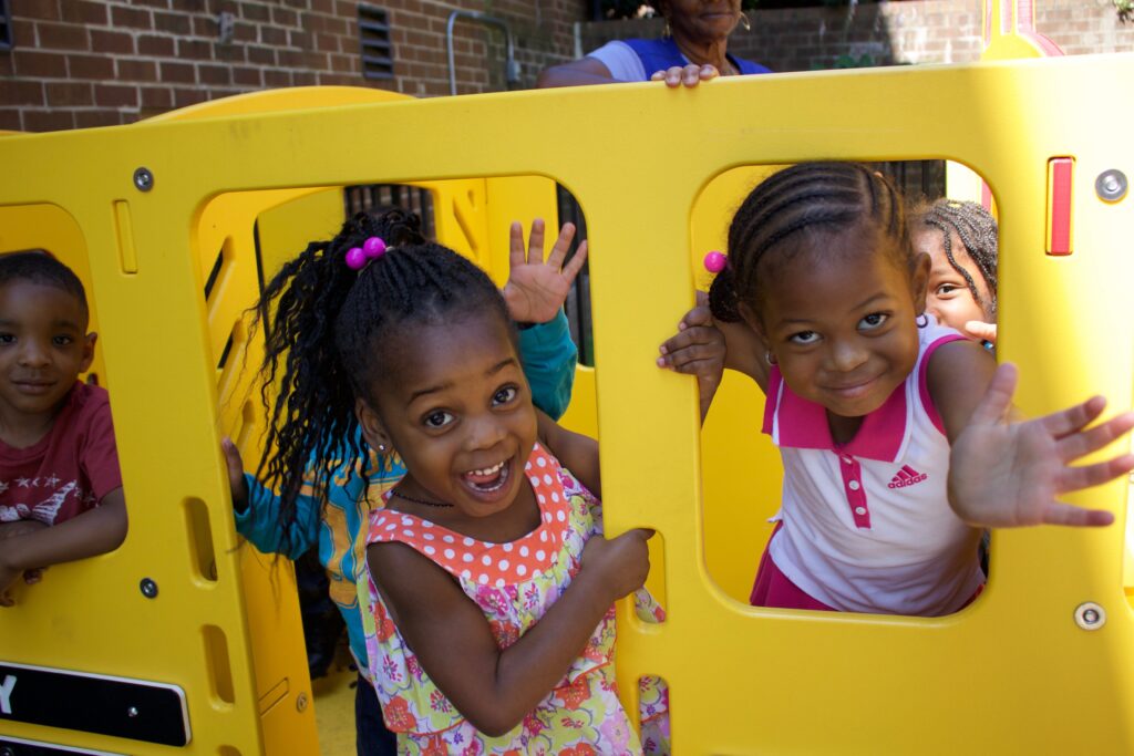 Young black children playing in a school bus structure