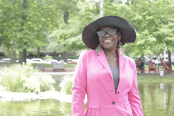 Alexis Scott smiling, standing in front of a small lake at a park