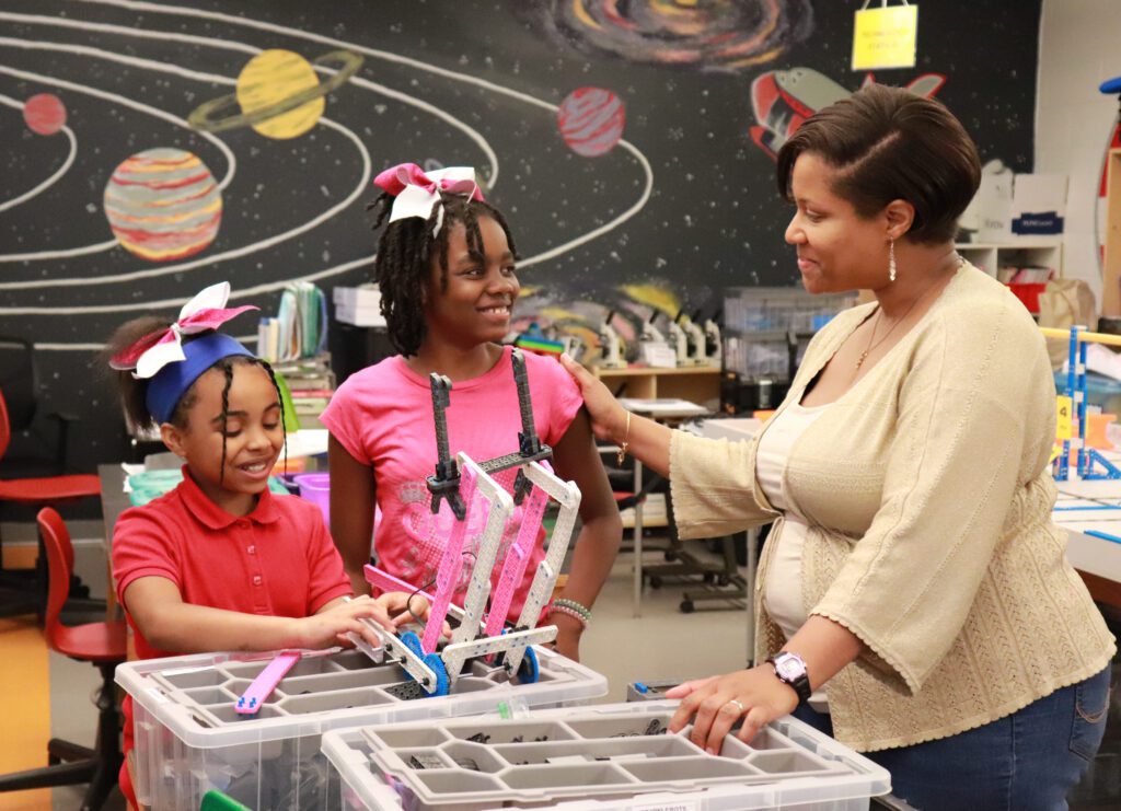 Teacher and two young students doing robotics