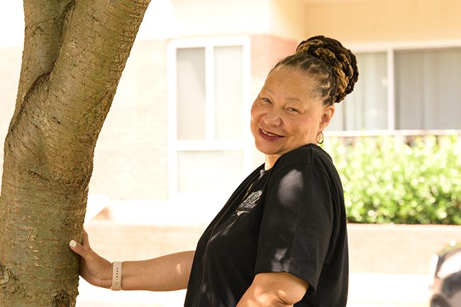 Gina Miller smiling next to a tree