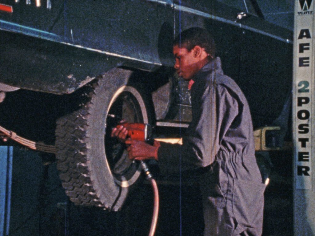 Young black mechanic putting a tire back on a car