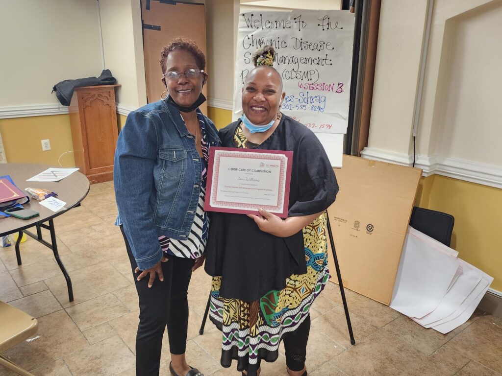 Two women, one holding a certificate of completion for a chronic disease self-management program workshop