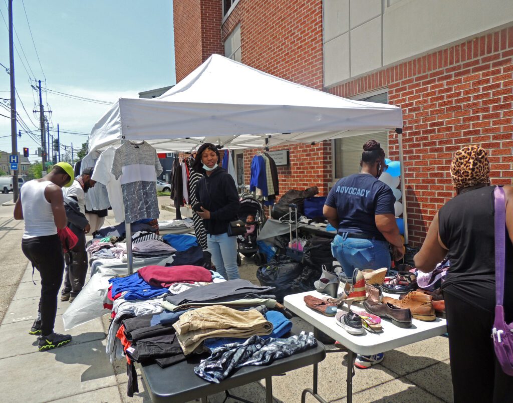 UPO volunteer giving away clothing at a booth on a sidewalk