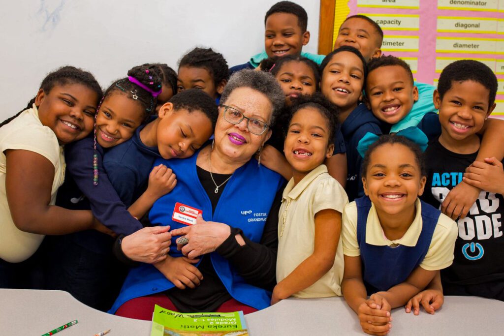 Group of children affectionately gathered around a UPO foster grandparent