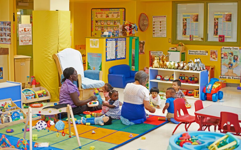 Two teachers playing with young children in a pre-school classroom