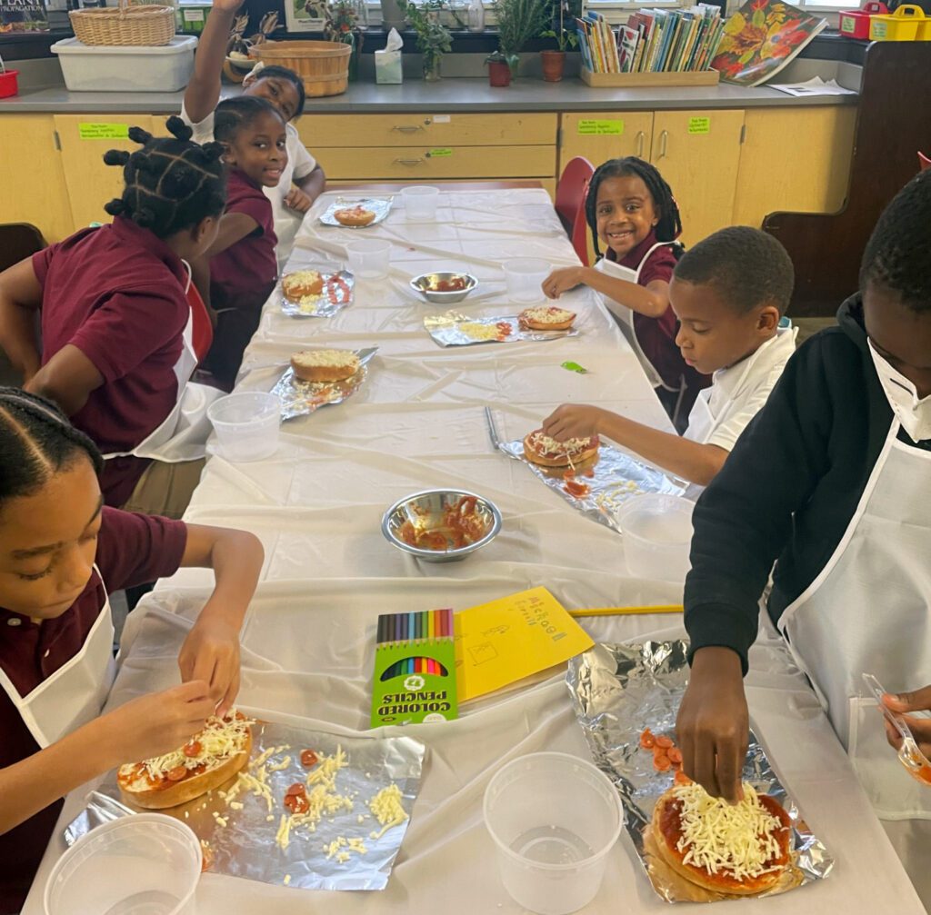 Group of children making small pizzas in school