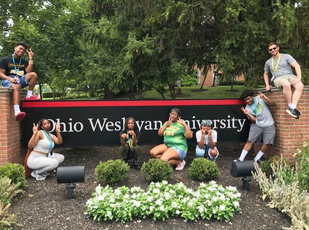 Group of kids posing in front of the Ohio Wesleyan University sign