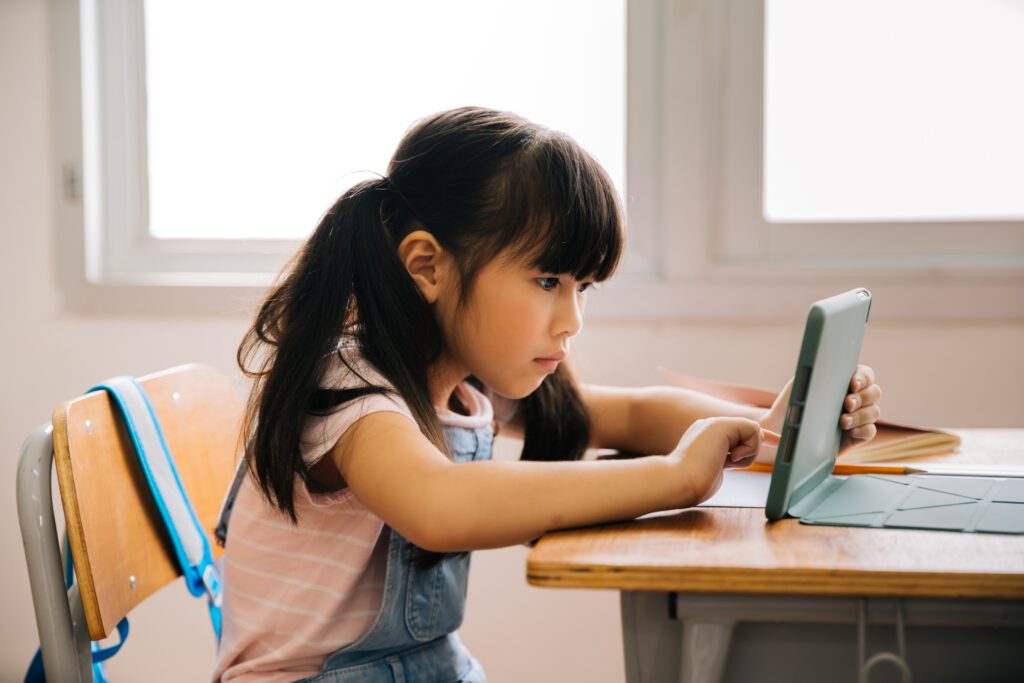 Asian elementary school girl with tablet in class