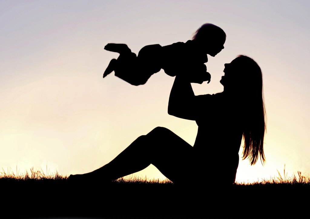 Silhouette of Happy Mother Playing Outside with Laughing Baby