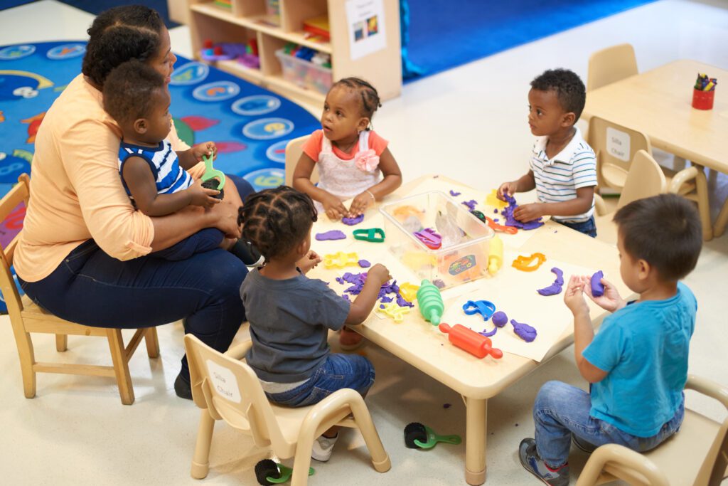 Woman teaching young children around a table with toys