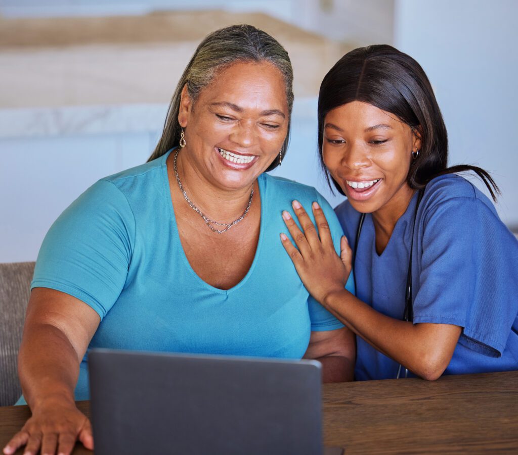 Happy senior woman and caregiver with laptop