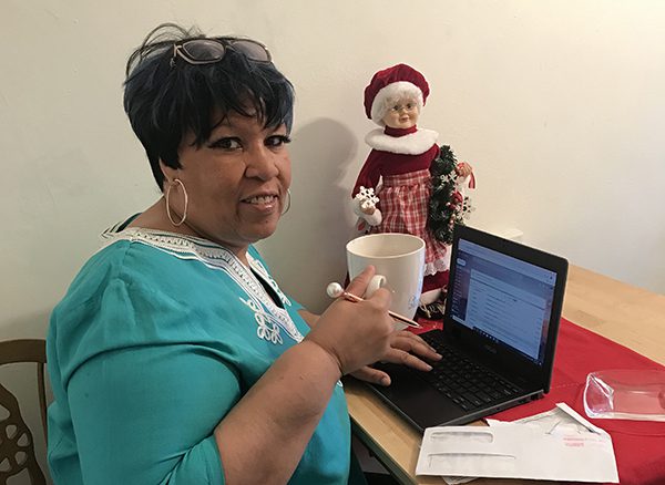 Sharon Gray-Rush sitting in front of her laptop with a cup of coffee