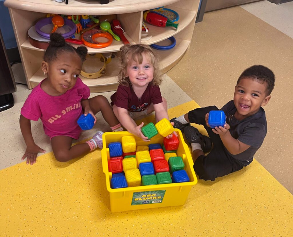 Three toddlers playing with blocks