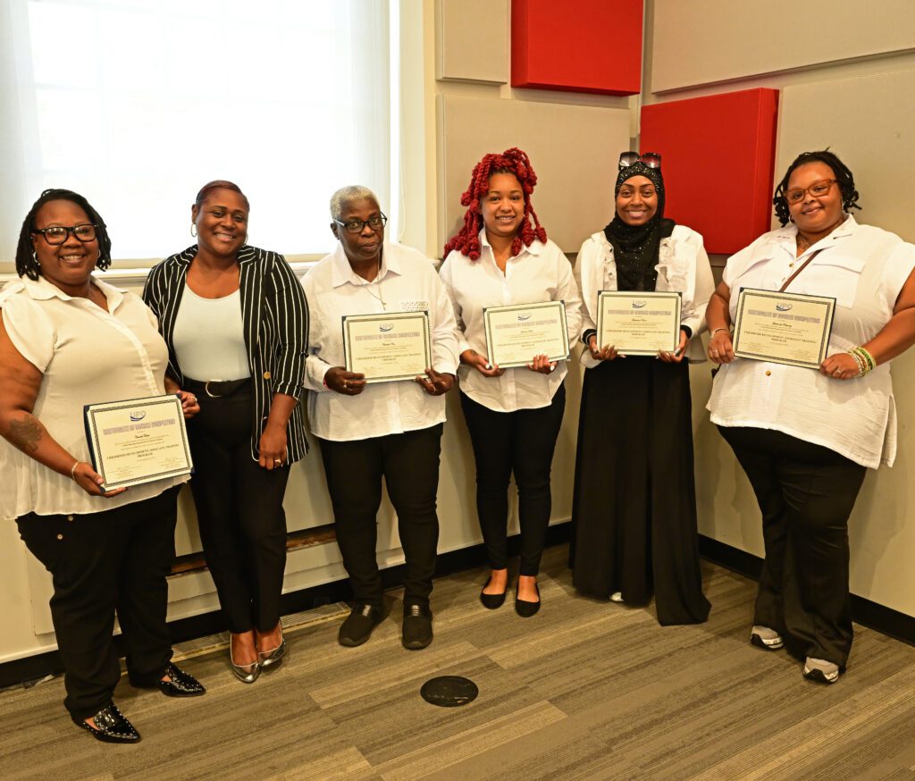 Group of women holding up certificates of completion with their teacher