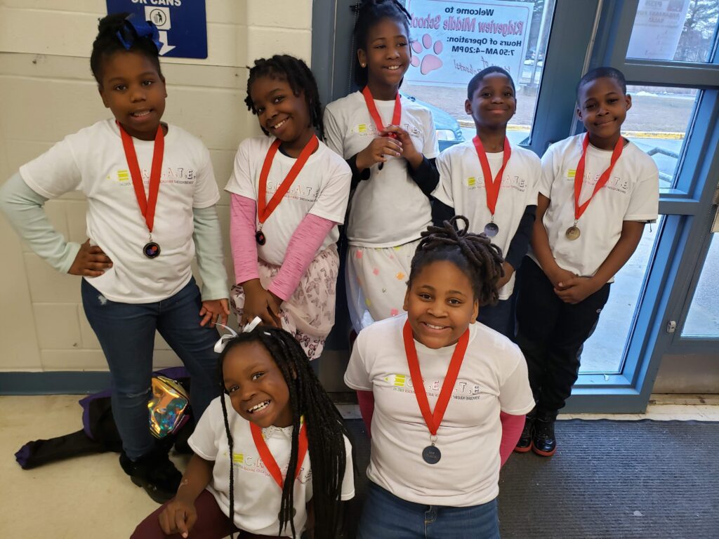 Young black children wearing CREATE program shirts and medals