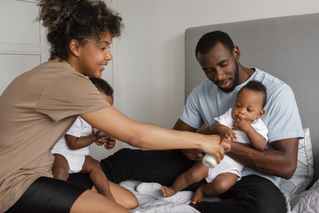 A mother feeding a baby that is being held by the father